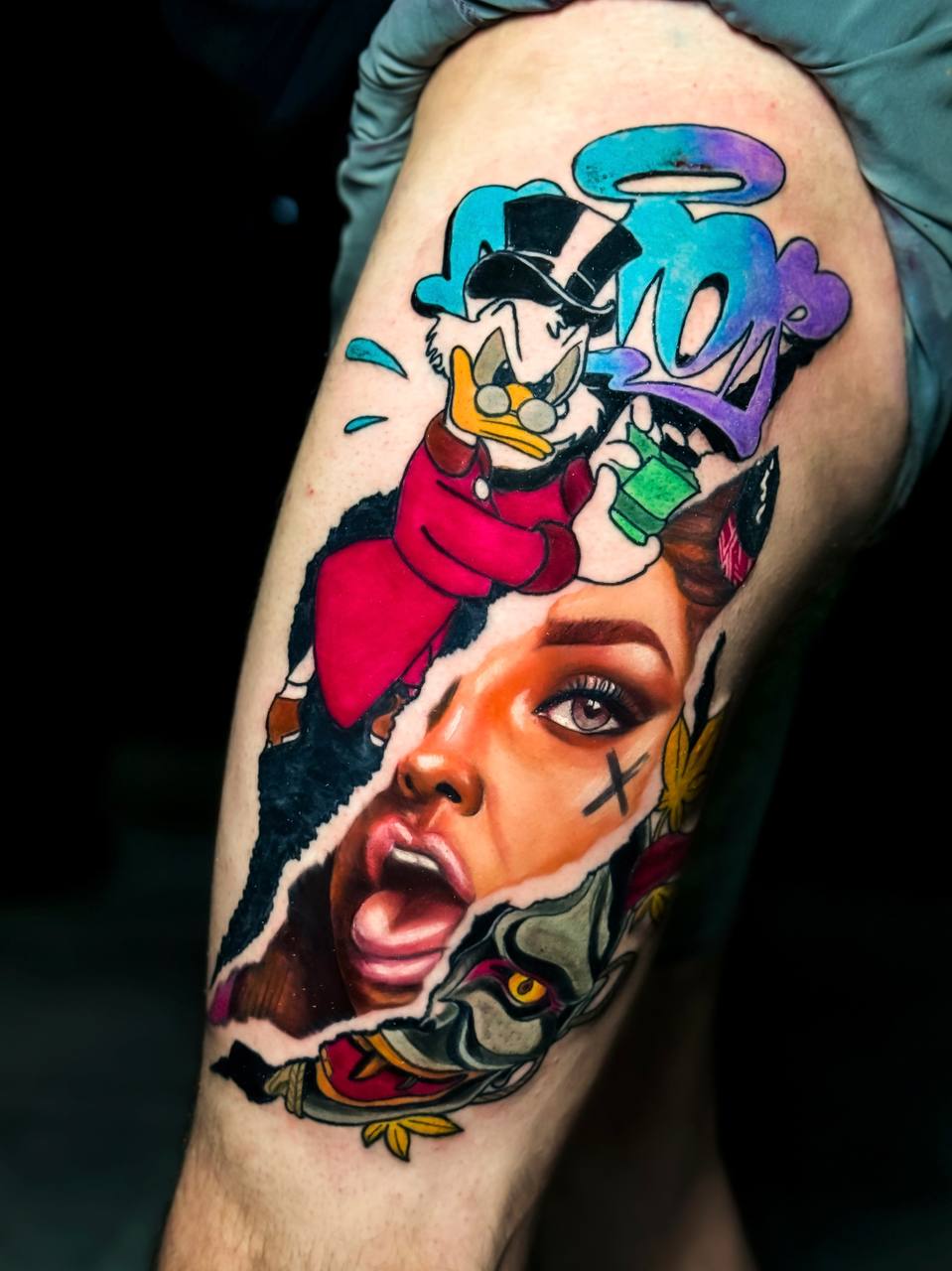 Bein mit farbigem Tattoo: Dagobert Duck und grafisch realistisches Frauengesicht, lebhaft.
