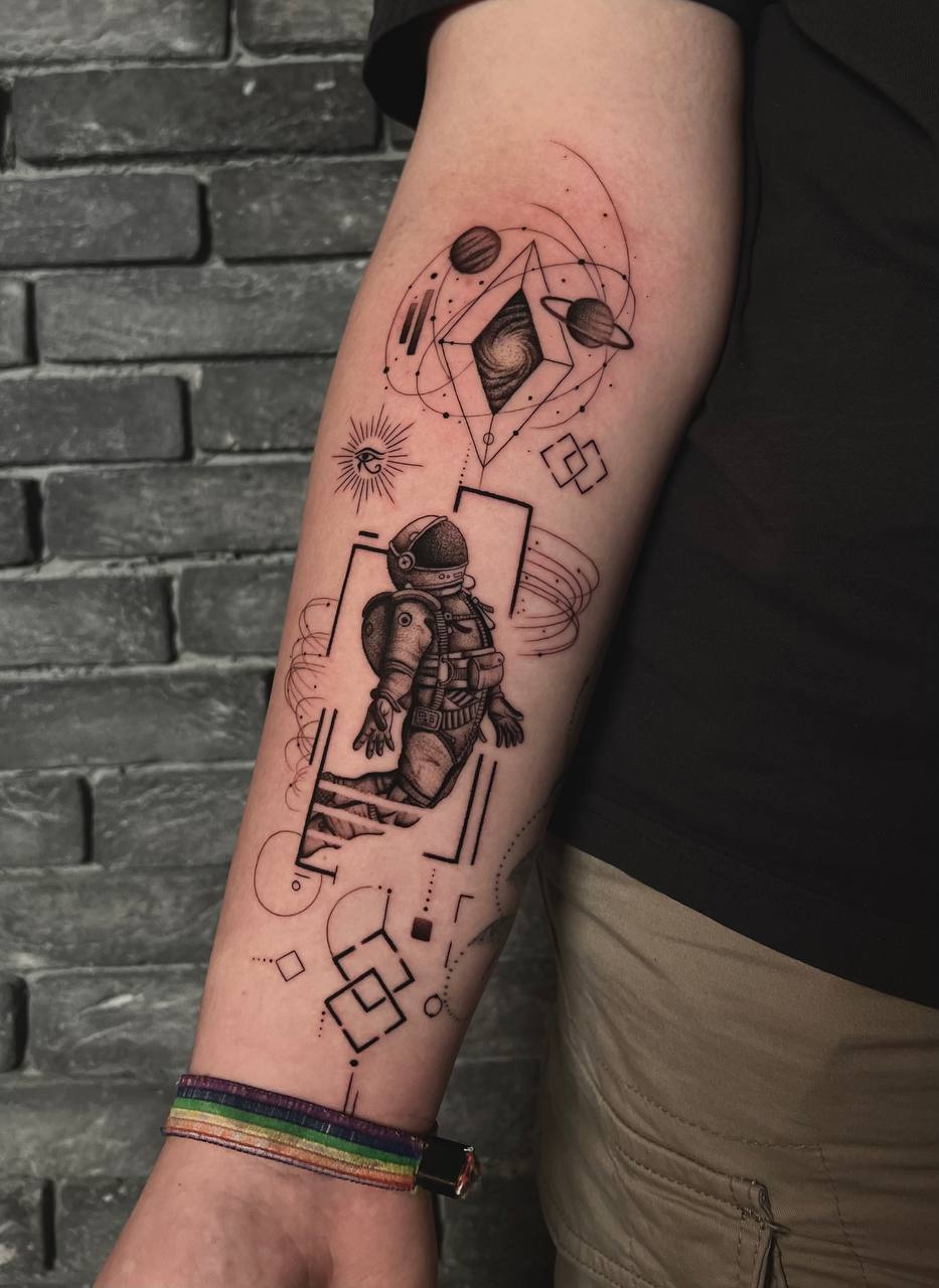 Arm mit Astronautentattoo, schwarz-weiß, geometrische Elemente, bunte Stoffarmbänder.