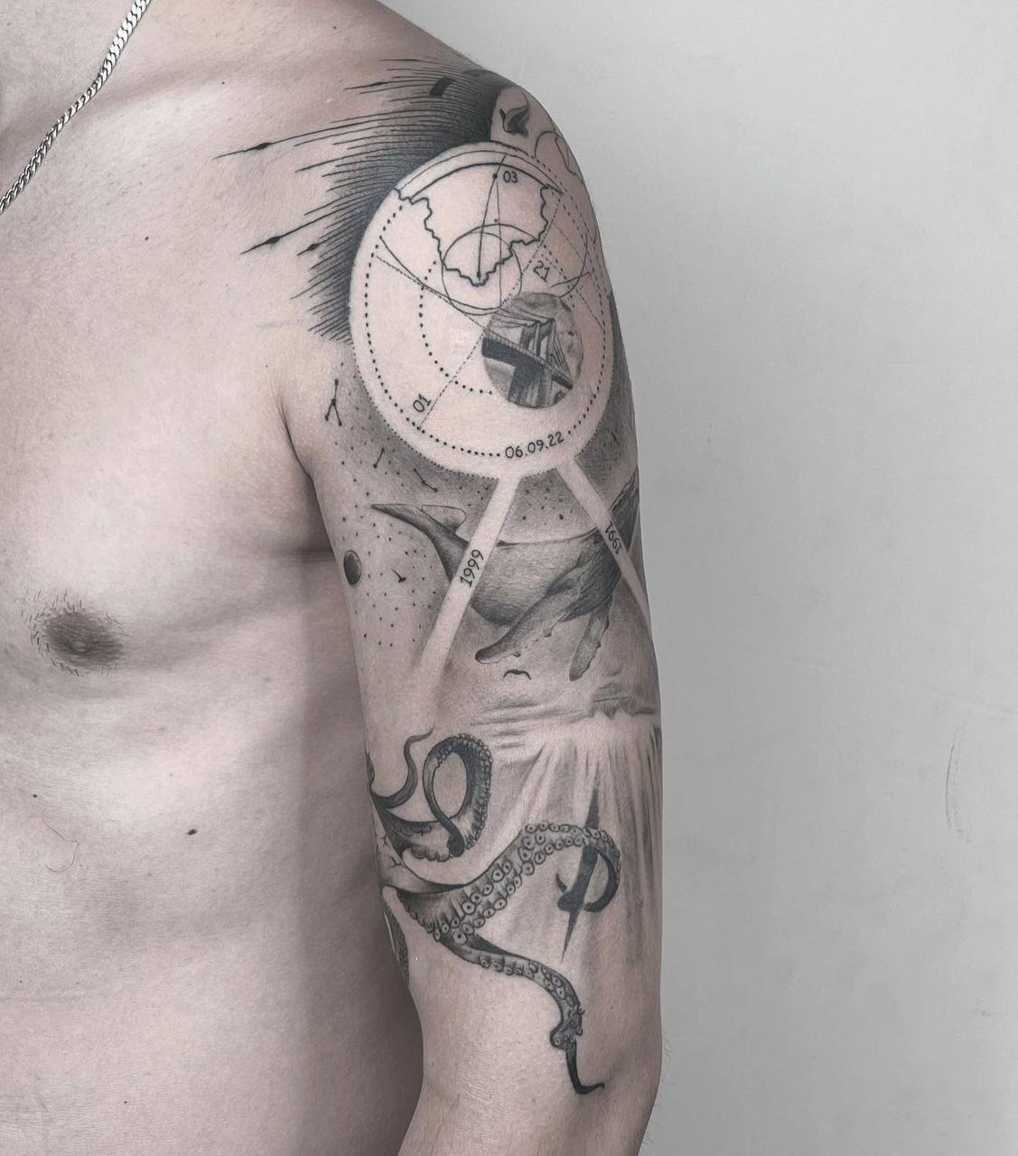 Mann mit komplexem Arm-Tattoo, schwarz-grau, planetarisches Design, Tentakel-Detail am Unterarm.