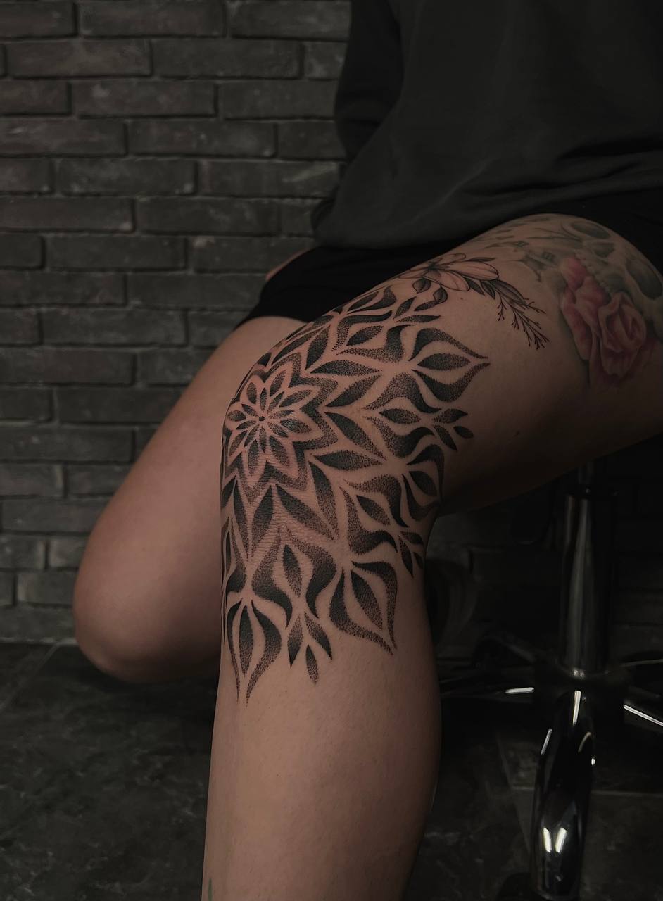Person mit Bein-Tattoo und grauer Wand, komplexes schwarz-graues Muster, interessante Textur.