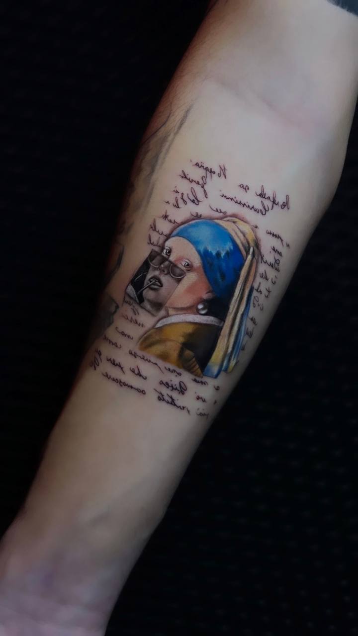 Tattoo auf Unterarm mit Gemälde-Frau; blau-gelbes Tuch, Schrift drumherum, dunkler Hintergrund.