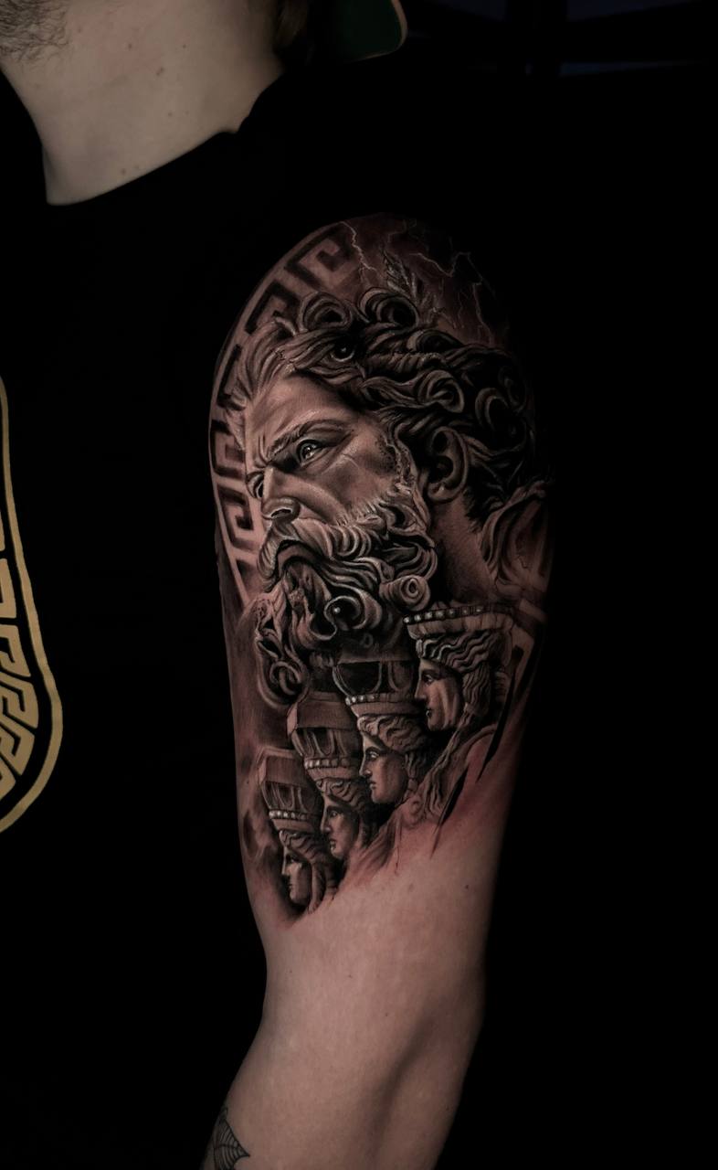 Tattoo eines majestätischen Mannes mit Bart, dramatischer Ausdruck und antiken Statuen, schwarz-grau.