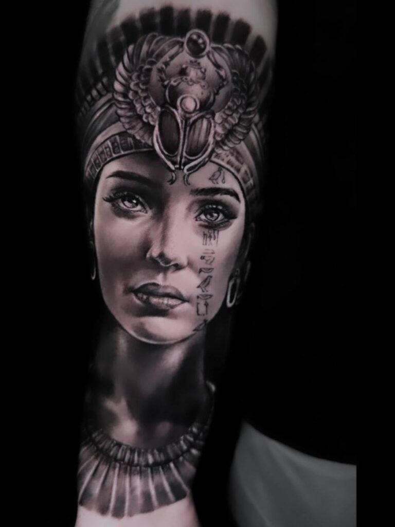 Schwarz-weißes Tattoo einer ägyptischen Figur mit ernstem Gesichtsausdruck und Pharaonen-Kopfschmuck.