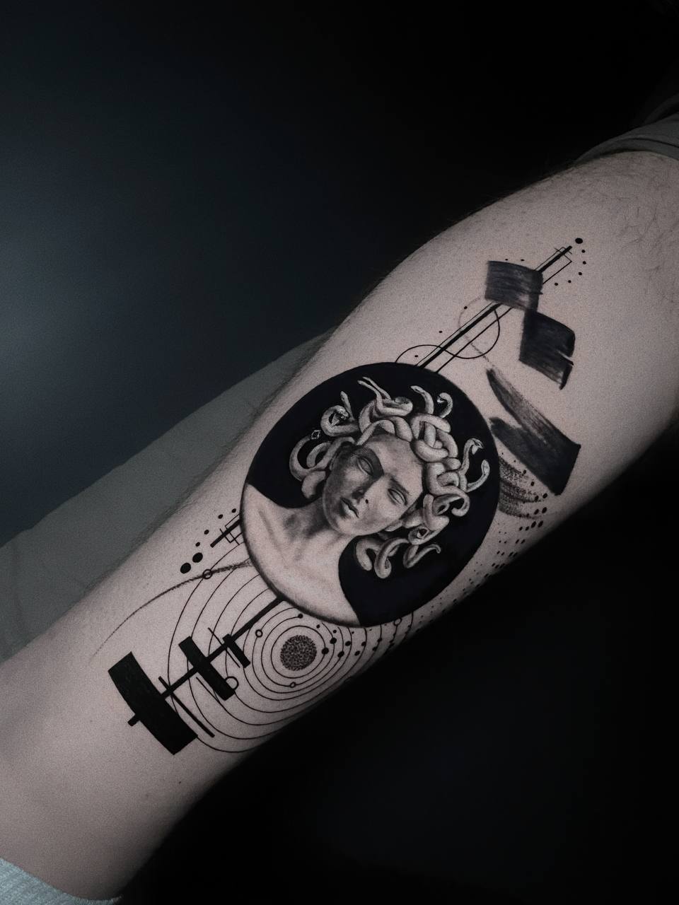 Schwarz-weißes Medusa-Tattoo mit geometrischen Mustern auf einem Arm.