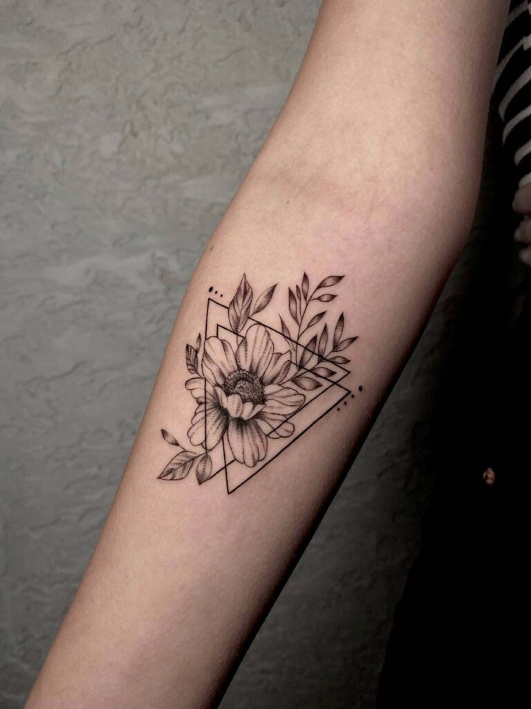 Schwarz-weiße Sonnenblumentätowierung mit geometrischen Formen auf einem Unterarm.