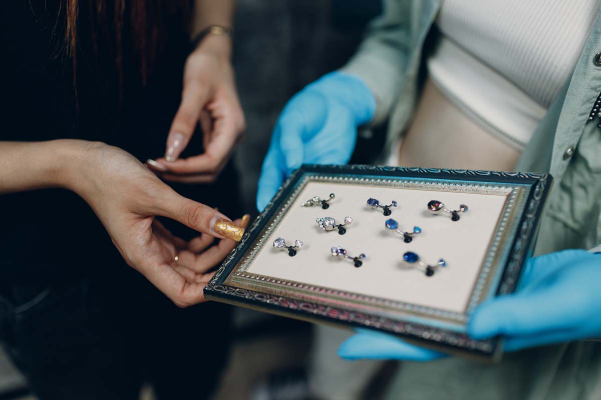 Personen betrachten Schmucktafeln, eine mit blauen Handschuhen, Nahaufnahme.