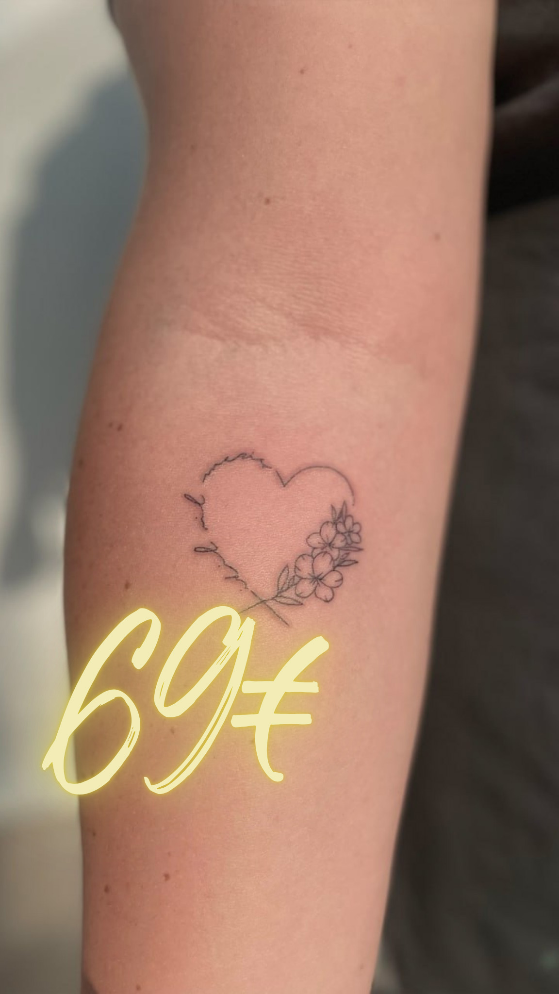 Tätowierung eines Herzens mit Blumen auf einem Arm, Preisangabe 69 Euro.