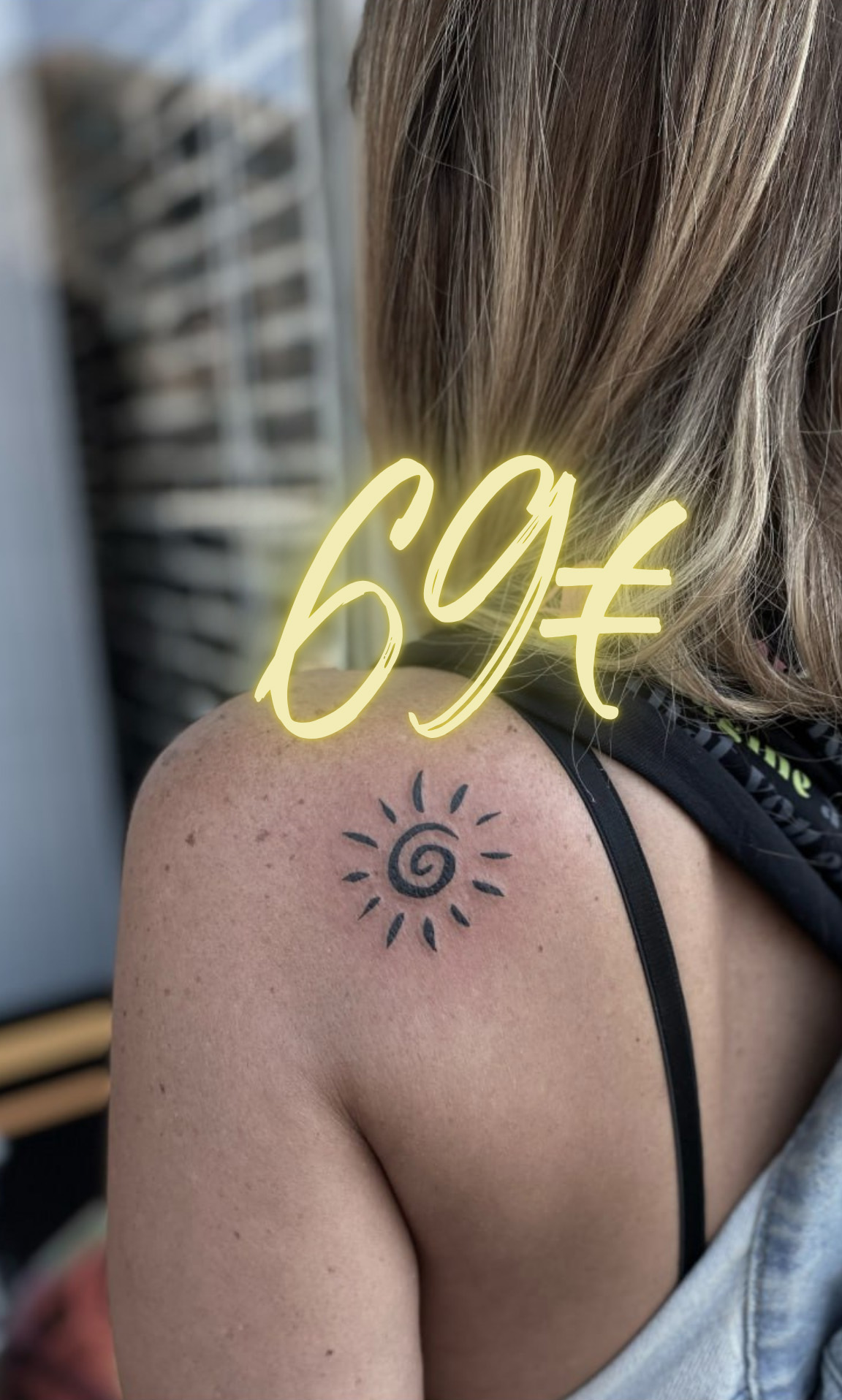Eine Person mit blonden Haaren zeigt ein Sonne-Tattoo auf der Schulter.